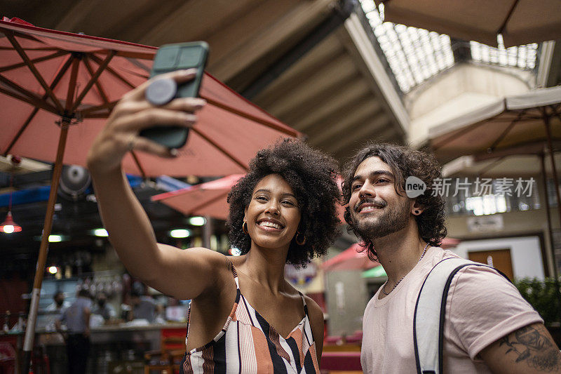 Portrait of beautiful tourist couple making selfie in the municipal market